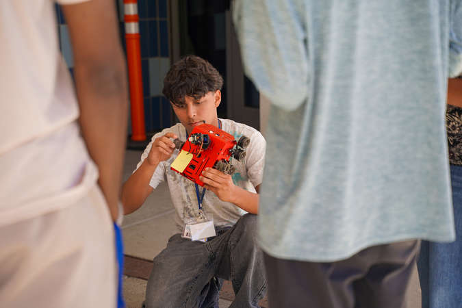 Academy attendee is shown making adjustments to a small robotic vehicle