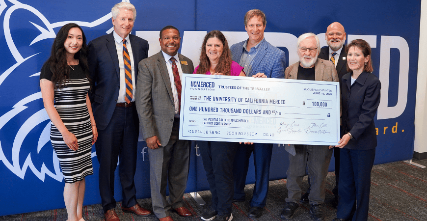 Leadership from Las Positas and UC Merced Board of Trustees pose with big check